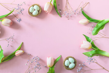 Frame of tulips, bird's nests on pink background; happy easter holiday greeting card