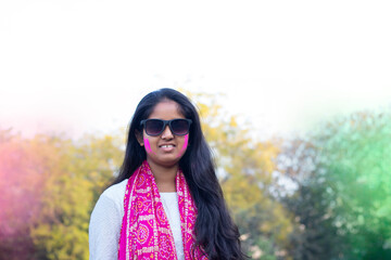 portrait of smiling young woman with colourful face and sunglass on Holi