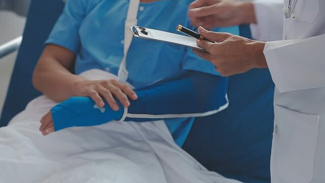 Man with broken arm in cast lying on bed in hospital. The emergency center treatment is plaster and hangs with sling for a further cure in an orthopedic clinic. Patient pain from accident injury.