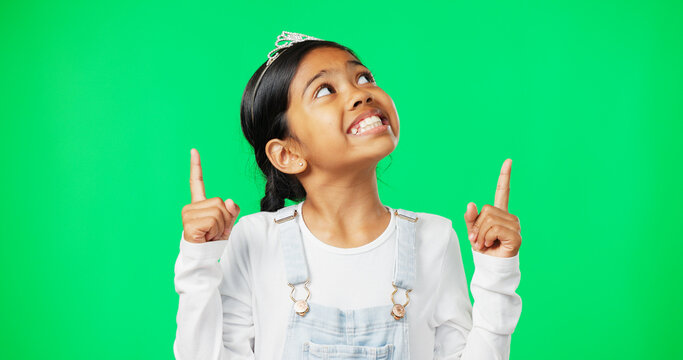 Green screen, mockup and child pointing up excited, happy and isolated in a studio background. Deal, sale and young girl or kid hands showing at brand, product placement or branding logo