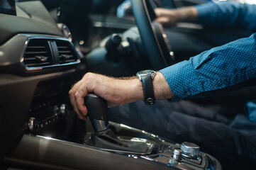 Close-up of a man's hand while shifting the automatic transmission of a car.