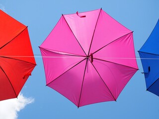 paraguas rosa fucsia abierto colgando en un día soleado