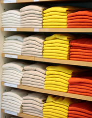 Stacks of colorful cashmere sweaters on shelves in retail store.