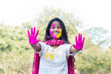 Young smart indian girl face coloured with gulal showing coloured palms