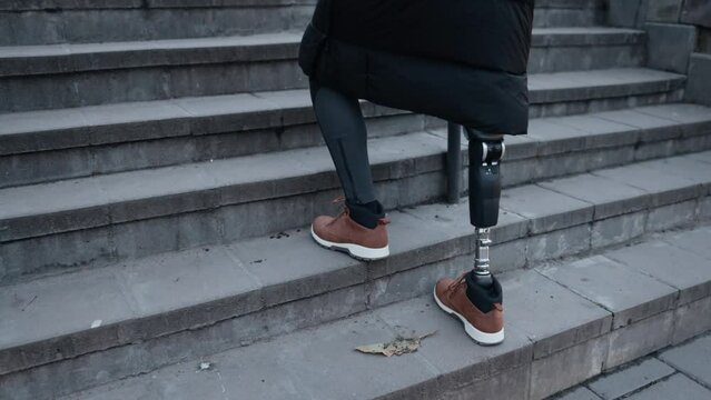Prosthetic leg, Disability climb, City stairs. Man with prosthetic leg and disability climbs stairs on city street.