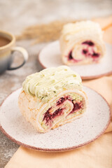 Roll biscuit cake with cream cheese and jam, cup of coffee on brown concrete, side view, selective focus.