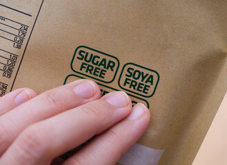 A woman holding a package with a Sugar Free and a Soya Free label on it.