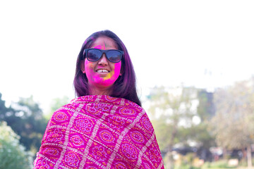 portrait of smiling young woman with colourful face and sunglass on Holi