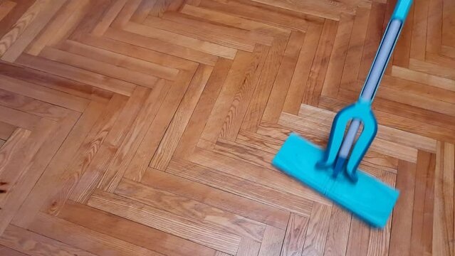 Wipe the parquet floor with a mop. House cleaning, cleanliness and order in the house. Housekeeping concept.
