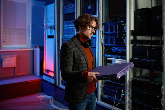Portrait of it specialist holding hardware in hand standing in server room