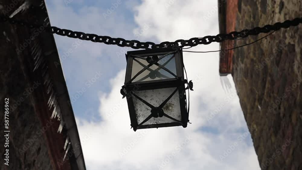 Poster ancient lantern on a chain in the walls of the castle