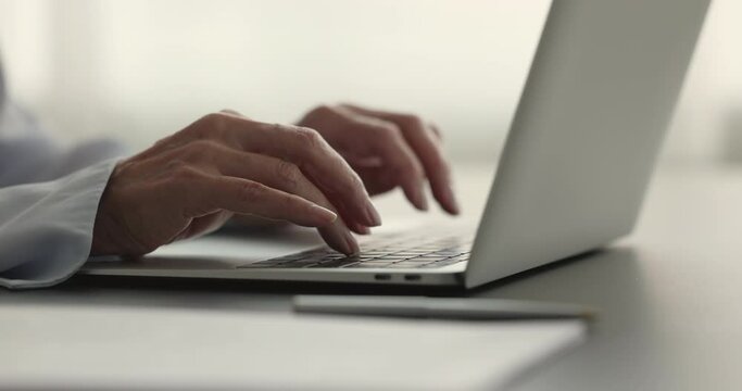 Elderly 60s businesswoman typing on laptop keyboard sit at desk, close up. Unknown office employee work on-line, lead correspondence to client remotely. Apps, technology, professional workflow online