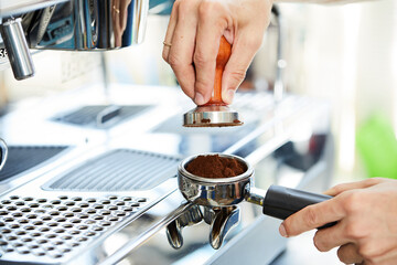 Fototapeta na wymiar barista's hands temper coffee against the background of a coffee machine