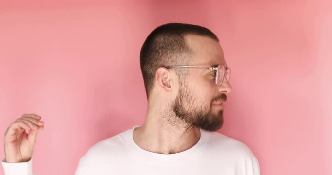 Handsome guy in eyeglasses standing and listening to someone scornfully, turn his head the other way, and say blah blah blah gesture isolated on pink color.