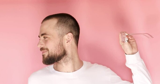 Handsome guy standing and listening to someone holds glasses in hand improvising a person, scornfully, turn his head the other way, and say blah blah blah gesture isolated on pink color.