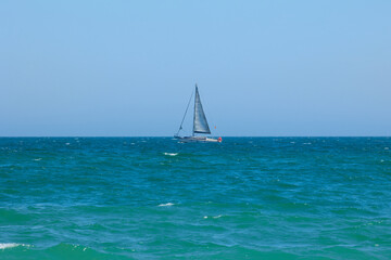 Blue Mediterranean Sea, clear skies and a sailing ship with white sailing. Regata