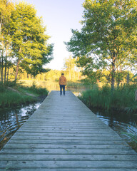 Man with yellow jacket soaking the beauty of nature over a jetty in a lake