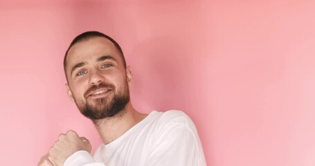 Carefree happy bearded man jumping dancing and singing, moving in quick dance rhythm while listening to favorite song, enjoying energetic vivid music. indoor studio shot isolated on pink background