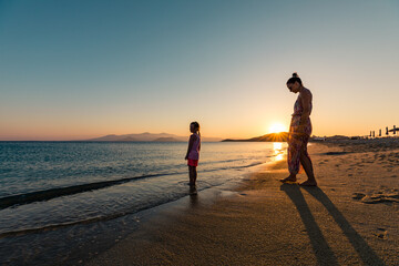 Naxos, Grece - July 20, 2020 - Mother and children watching amazing sunset over Naxos Island