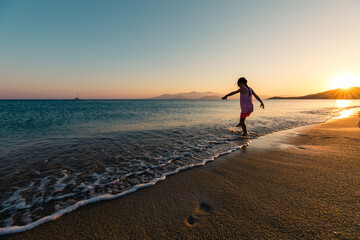 Naxos, Grece - July 20, 2020 - Girl having fun at beach during sunset over Naxos Island