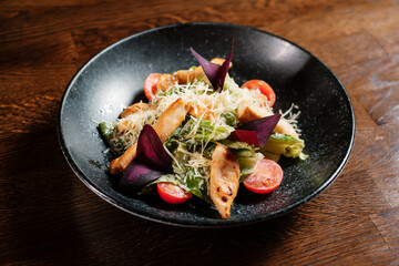 Baked fish salad with vegetables on black plate
