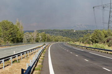 Fototapeta premium virage d'autoroute sans voiture avec présence d'un pylone électrique, et un ciel nuageux du fait d'incendie 