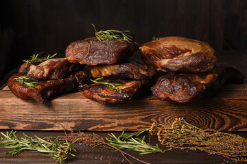 Dried Processed Beef Jerky with herbs and spices on wooden board against black background.