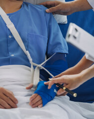 Man with broken arm in cast lying on bed in hospital. The emergency center treatment is plaster and hangs with sling for a further cure in an orthopedic clinic. Patient pain from accident injury.