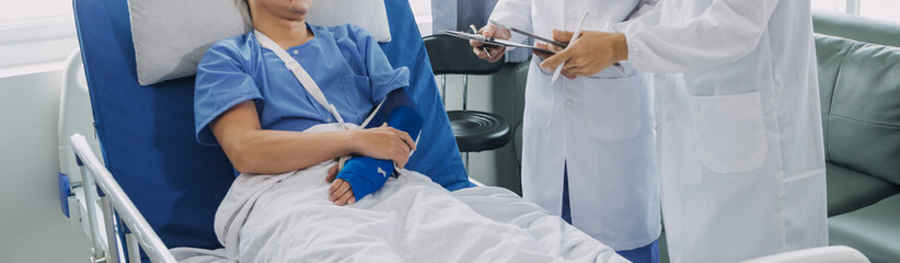 Man with broken arm in cast lying on bed in hospital. The emergency center treatment is plaster and hangs with sling for a further cure in an orthopedic clinic. Patient pain from accident injury.