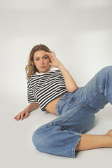 Fashion portrait of young woman in relaxed wide jeans and striped t shirt on the white background