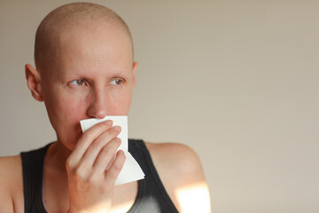 Bald cancer sick woman blowing running nose got flu cough cold, rhinitis sneezing in tissue or nosebleeds. Female is sick allergic having allergy symptoms coughing holding napkin. Misery, infelicity