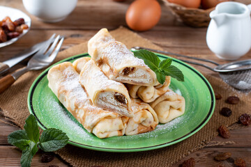 Thin pancakes with cottage cheese and raisins on wooden table. Healthy traditional breakfast concept.