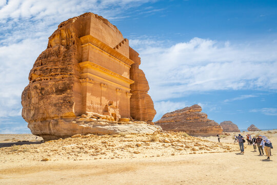 Group of tourists in front of Tomb of Lihyan, son of Kuza carved in rock in the desert,  Mada'in Salih, Hegra, Saudi Arabia