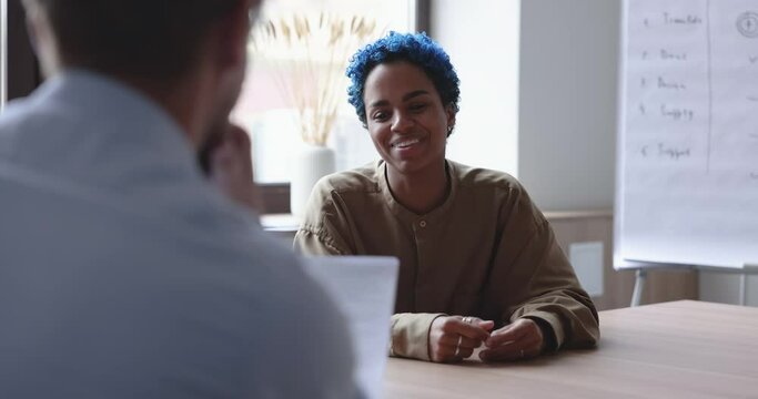 Young African Woman Applicant With Blue Hair Pass Job Interview In Office At Formal Meeting, Answer Questions, Talk To HR Manager. Business Negotiations, Human Resources, Communication, Qualification