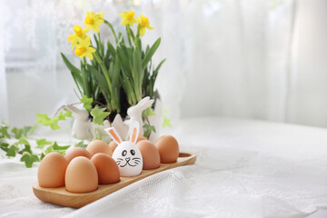 ten eggs on white table with yellow Narcissus flowers white rabbit egg painted with ears among...