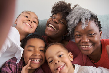 Obraz premium Happy african horizontal extended family smiling and taking a selfie at home.