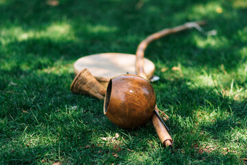 berimbau, instrumento musical brasilero para practicar y bailar capoeira, dejado en un pasto verde natural en d&iacute;a soleado al aire libre.