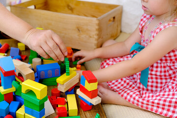 mother and daughter play together, build a city from colored parts, figures, blocks, kindergarten games, concept of childhood, earlier child development, creativity, early training