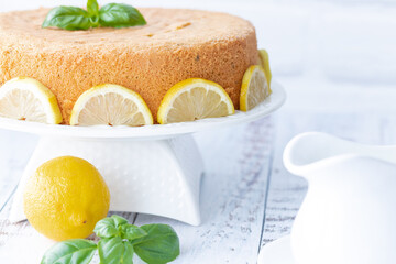 Basil and lemon cake in front of a white brick