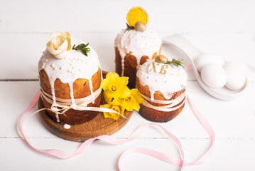 Easter cakes with, light, modern design on a white wooden back with yellow daffodils. Easter food. Easter symbol