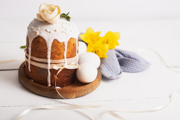 Obraz na płótnie Canvas Easter cakes with, light, modern design on a white wooden back with yellow daffodils. Easter food. Easter symbol