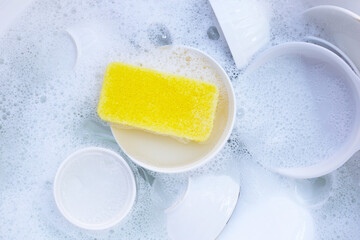 Dishes and bowls in water and bubbles of dishwashing liquid