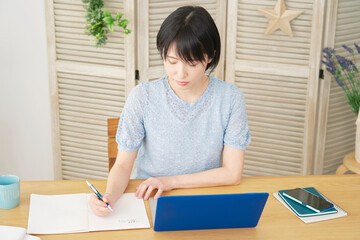 自宅でノートパソコンを使って勉強する女性