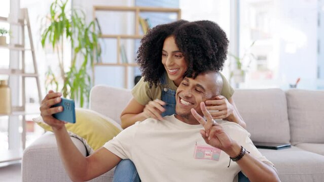 Couple, selfie and peace sign with kiss in home living room, bonding and care. V hand gesture, happiness and man and woman taking photo for funny memory, profile picture or social media with emoji.