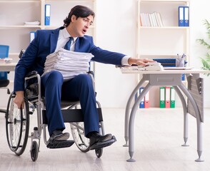 Young male employee in wheelchair working in the office