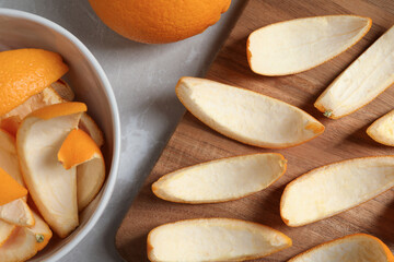 Many orange peels preparing for drying and fruit on grey textured table, flat lay