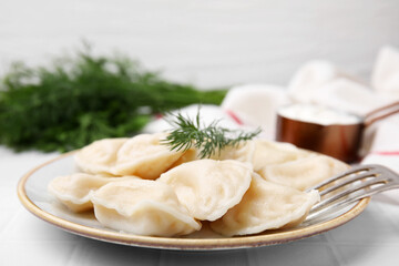Cooked dumplings (varenyky) with tasty filling and dill on white table, closeup