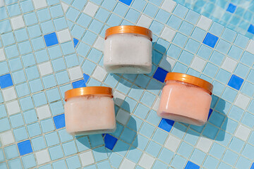 Varios frascos de crema con piscina en fondo aislado. Vista superior en dia soleado. Copy space....