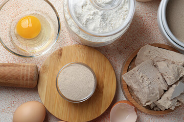 Different types of yeast, flour and eggs on orange textured table, flat lay