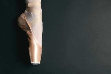 Ballerina in pointe shoe on black background, closeup. Space for text
